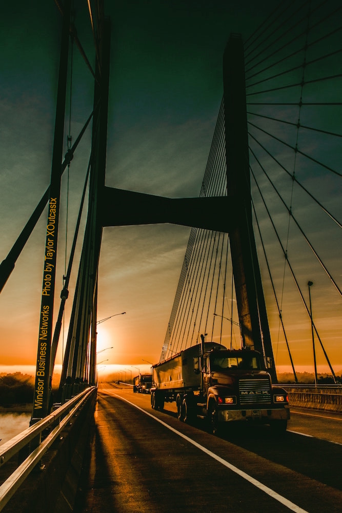 Trucks Crossing a Bridge at Sunset